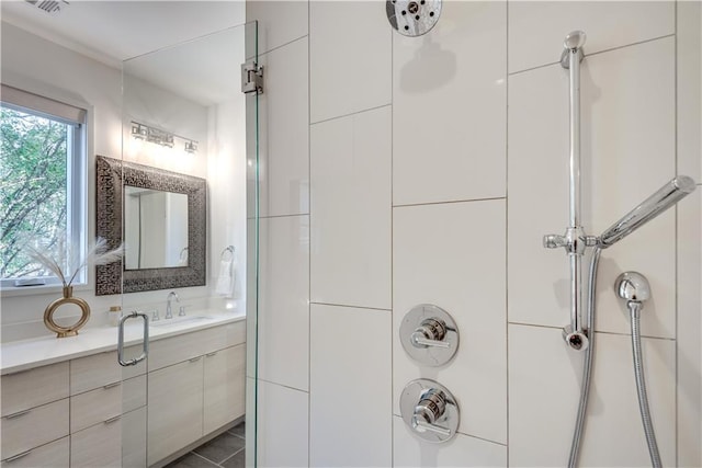 full bath featuring vanity, a shower, and visible vents