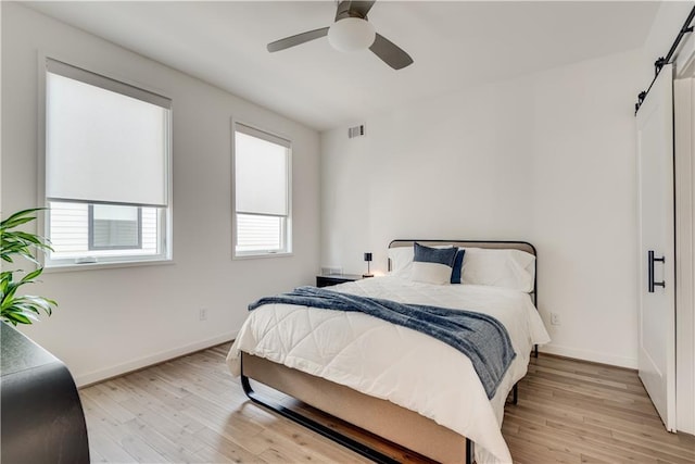 bedroom featuring baseboards, visible vents, ceiling fan, and light wood finished floors