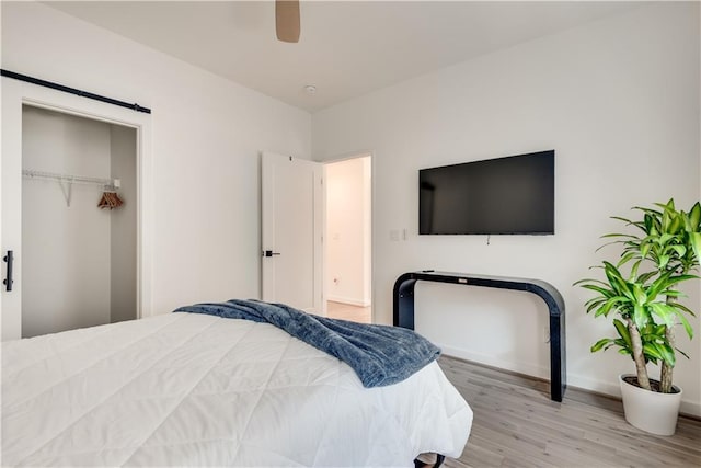 bedroom with a ceiling fan, baseboards, wood finished floors, and a closet