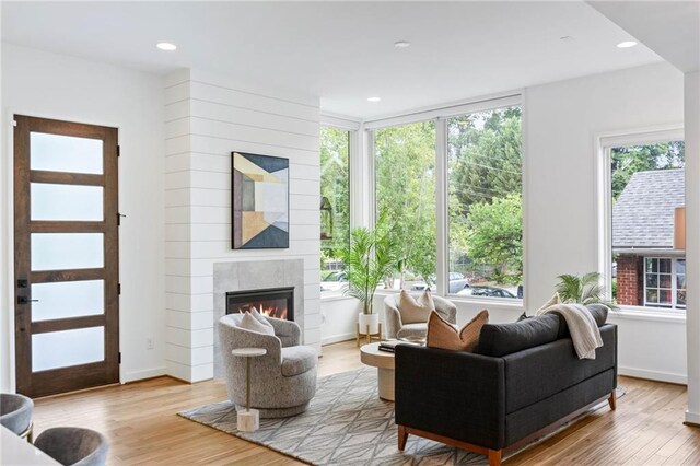 living room featuring recessed lighting, a glass covered fireplace, wood finished floors, and a wealth of natural light
