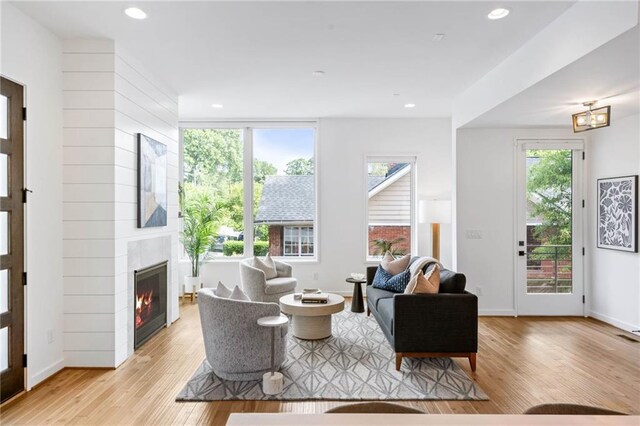 living area featuring light wood-style floors, recessed lighting, baseboards, and a fireplace
