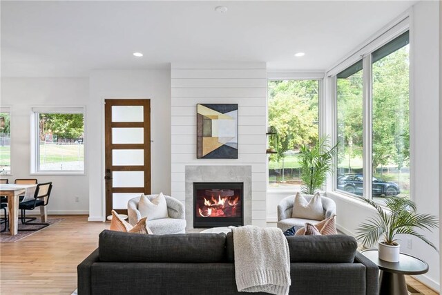 living room with recessed lighting, baseboards, a large fireplace, and light wood-style floors