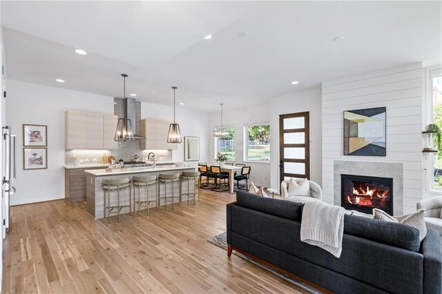 living area featuring light wood-style floors, a glass covered fireplace, and recessed lighting