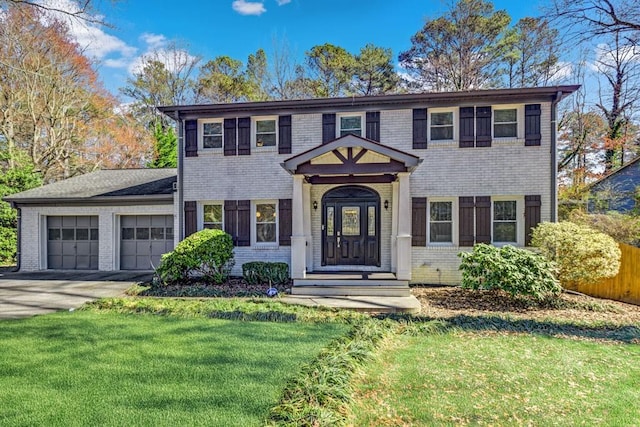 colonial house with a garage, driveway, a front lawn, and brick siding