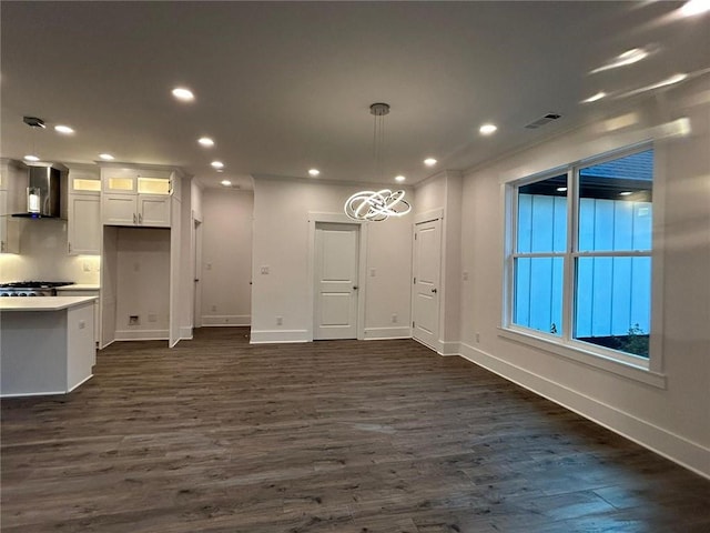 interior space with wall chimney range hood, white cabinetry, decorative light fixtures, and dark wood-type flooring