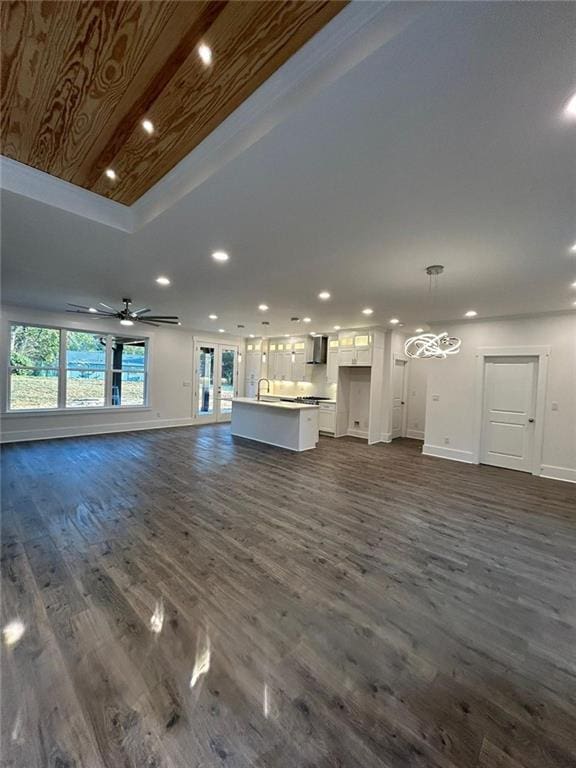 unfurnished living room with lofted ceiling, sink, ceiling fan with notable chandelier, and dark hardwood / wood-style flooring