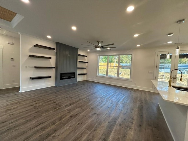 unfurnished living room featuring dark hardwood / wood-style floors, sink, and ceiling fan