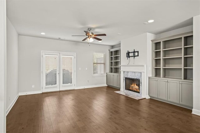 unfurnished living room featuring a fireplace, dark hardwood / wood-style flooring, and ceiling fan