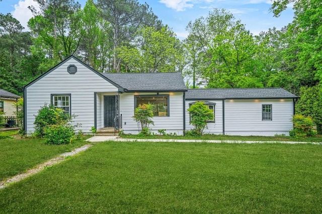 ranch-style house featuring a shingled roof and a front yard
