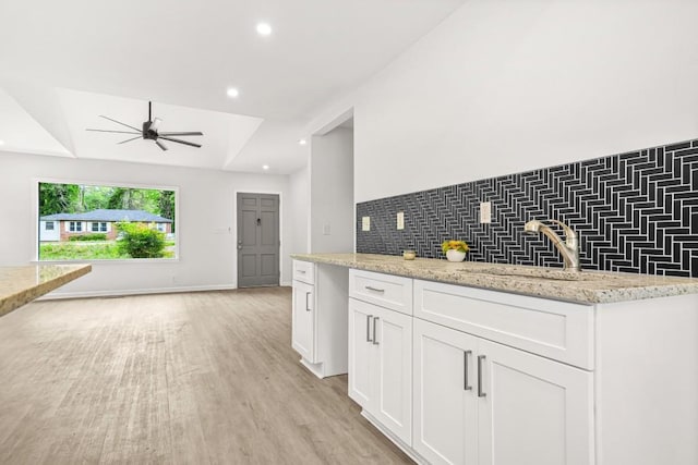 kitchen with ceiling fan, tasteful backsplash, a sink, light wood finished floors, and white cabinetry