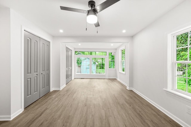 interior space with baseboards, recessed lighting, wood finished floors, and multiple windows