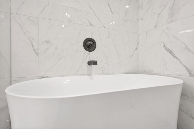 bathroom featuring tile walls and a soaking tub