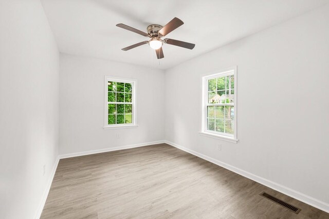 empty room with visible vents, plenty of natural light, and wood finished floors