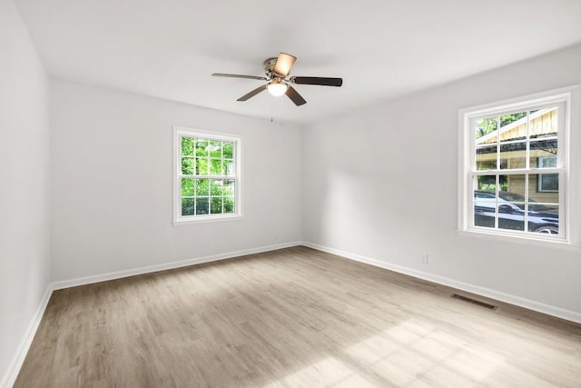 spare room with a ceiling fan, baseboards, visible vents, and wood finished floors