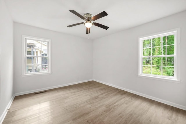 unfurnished room featuring visible vents, baseboards, wood finished floors, and a wealth of natural light
