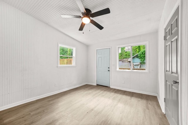 empty room featuring baseboards, a ceiling fan, wood finished floors, and a wealth of natural light