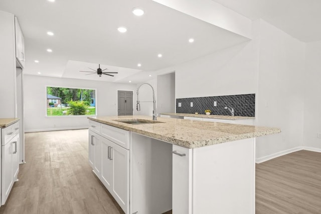 kitchen with a sink, recessed lighting, white cabinets, and light wood-type flooring