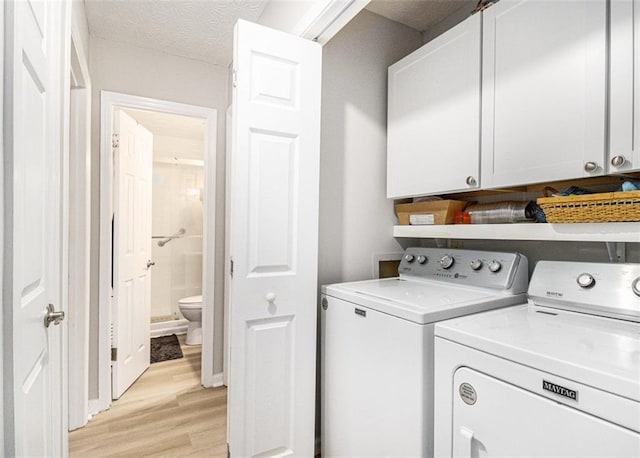 laundry room with separate washer and dryer, cabinets, a textured ceiling, and light wood-type flooring