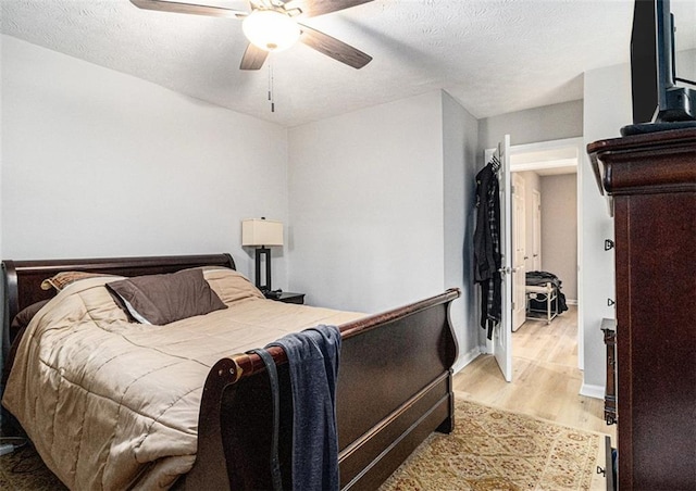 bedroom featuring ceiling fan, a textured ceiling, and light wood-type flooring