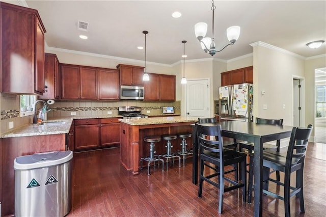 kitchen with a sink, dark wood finished floors, stainless steel appliances, a kitchen island, and visible vents