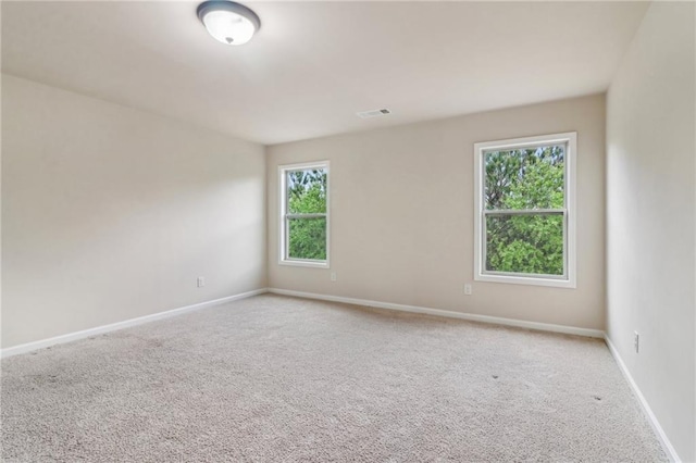 carpeted empty room featuring baseboards and visible vents