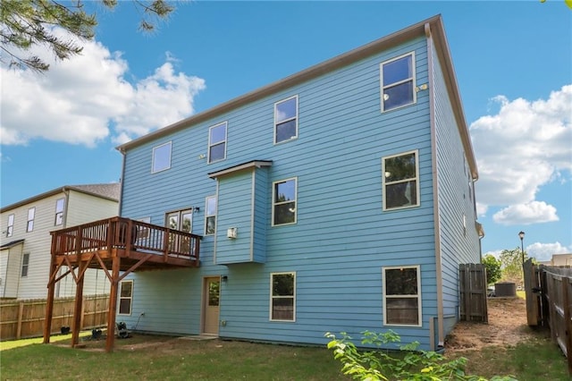 rear view of property with a fenced backyard, a yard, central AC, and a deck