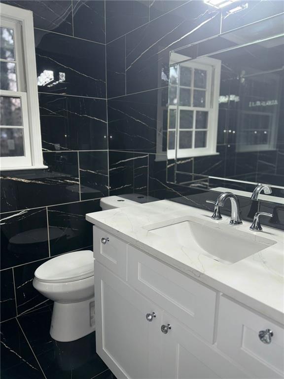 bathroom with tile walls, vanity, and toilet