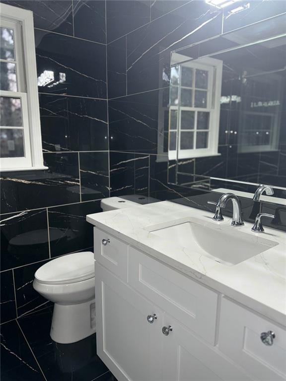 bathroom with vanity, tile walls, and toilet