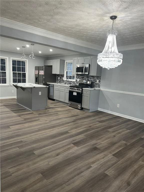 kitchen with decorative light fixtures, appliances with stainless steel finishes, dark hardwood / wood-style flooring, gray cabinets, and backsplash