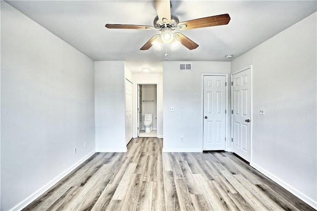 unfurnished bedroom with light wood finished floors, visible vents, a ceiling fan, ensuite bath, and baseboards