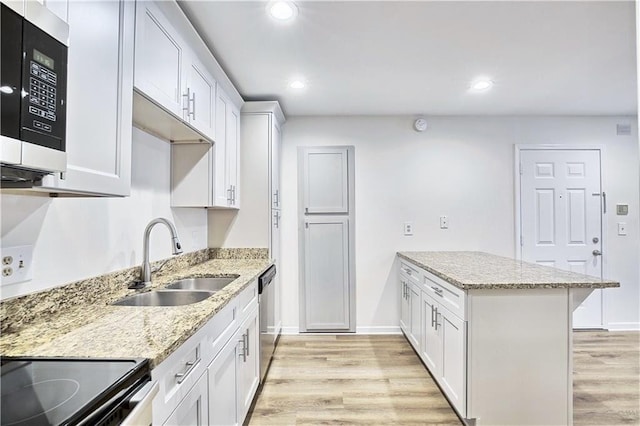 kitchen with recessed lighting, appliances with stainless steel finishes, a sink, light wood-type flooring, and a peninsula