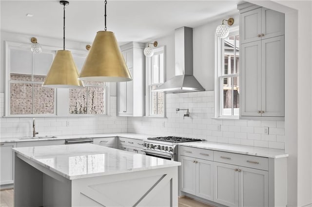 kitchen with wall chimney exhaust hood, light hardwood / wood-style flooring, stainless steel stove, sink, and decorative backsplash