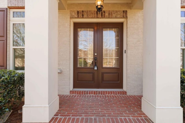 view of exterior entry featuring french doors and brick siding