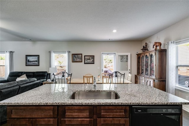 kitchen featuring plenty of natural light, black dishwasher, and a kitchen island with sink