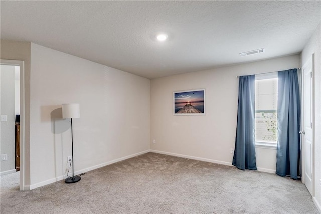 unfurnished room with light carpet and a textured ceiling