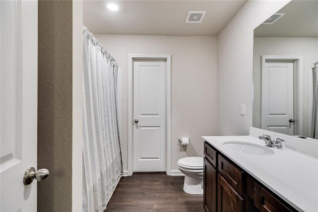 bathroom with vanity, wood-type flooring, and toilet