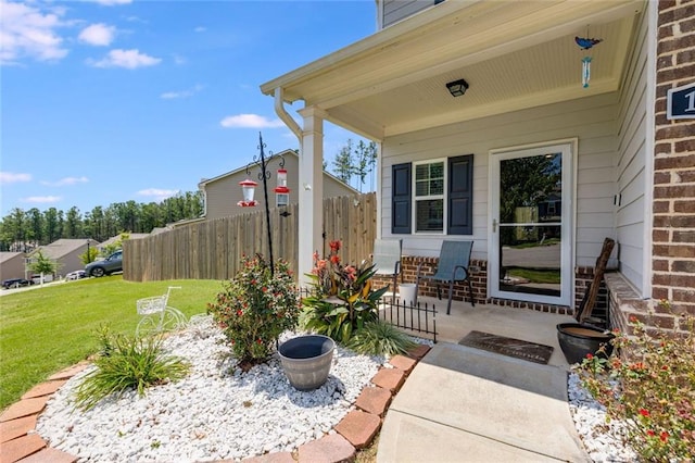 entrance to property with covered porch and a yard