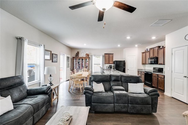 living room with ceiling fan and dark wood-type flooring