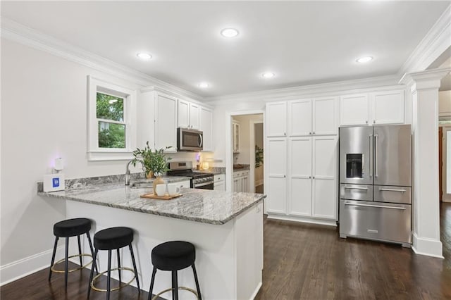 47 Oakridge Ave SE, Atlanta, GA 30317 - kitchen featuring appliances with stainless steel finishes, a peninsula, light stone counters, white cabinets, and crown molding