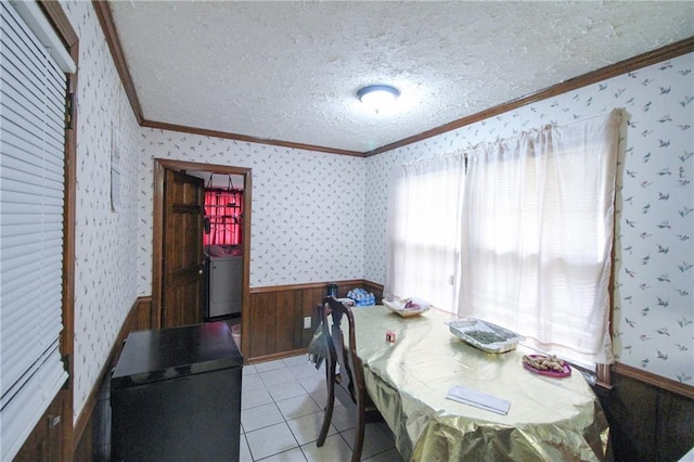 dining area with a textured ceiling, wallpapered walls, washer / clothes dryer, crown molding, and light tile patterned floors
