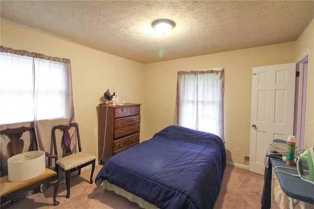 bedroom featuring carpet flooring, a textured ceiling, and multiple windows