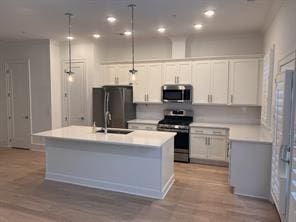 kitchen featuring white cabinets, decorative light fixtures, sink, and stainless steel appliances