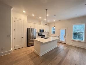 kitchen featuring pendant lighting, sink, an island with sink, appliances with stainless steel finishes, and white cabinetry