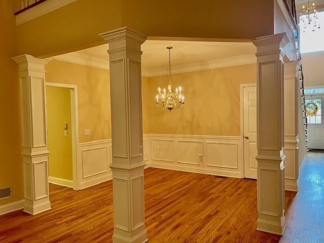 interior space featuring wood-type flooring, crown molding, and a notable chandelier