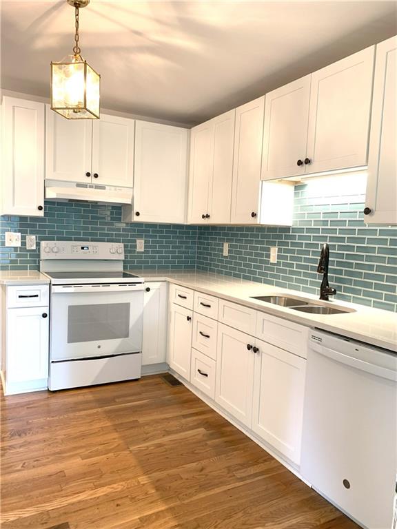 3604 Orchard Cir, Decatur, GA 30032 - kitchen featuring white appliances, under cabinet range hood, light countertops, white cabinets, and decorative backsplash