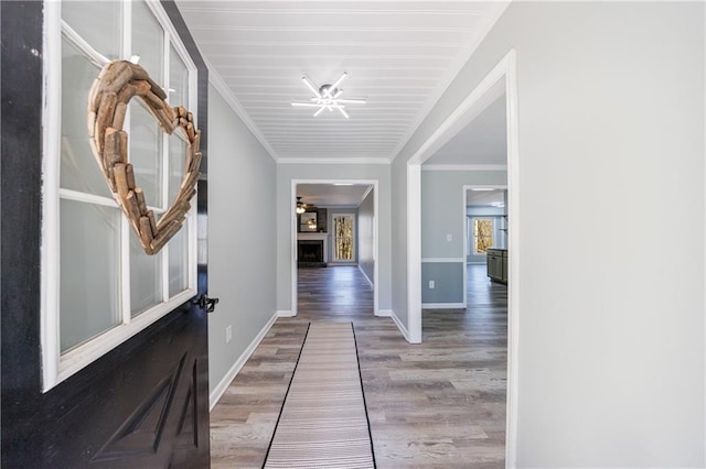 hallway with ornamental molding, baseboards, and wood finished floors