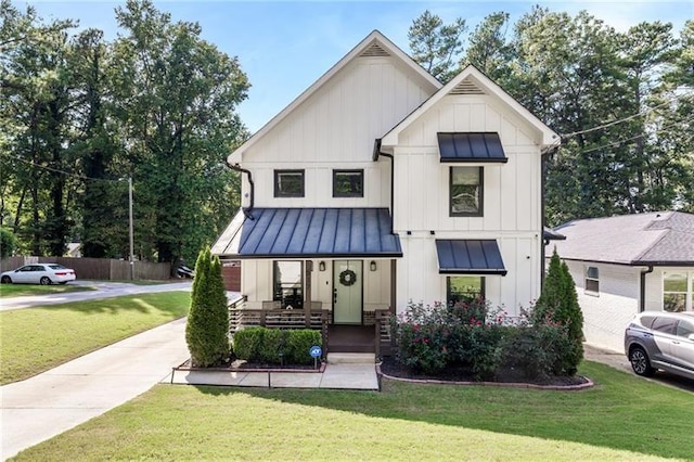 modern inspired farmhouse with a standing seam roof, a front lawn, and board and batten siding