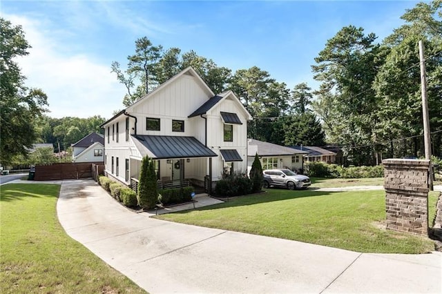 modern farmhouse style home with metal roof, a standing seam roof, a front yard, and board and batten siding