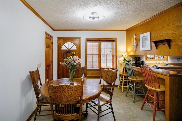 dining room with a textured ceiling, baseboards, and ornamental molding