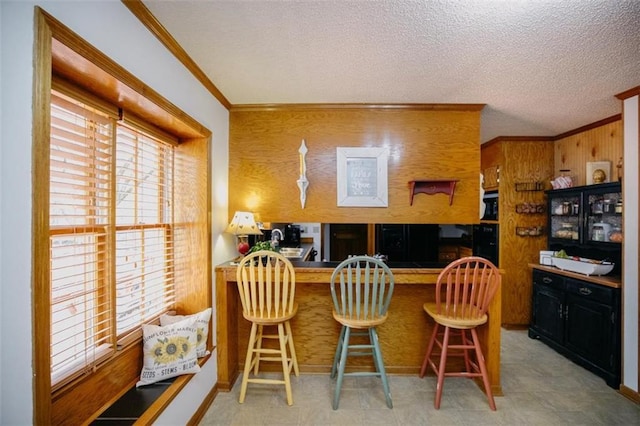 kitchen with crown molding, a kitchen breakfast bar, and a textured ceiling